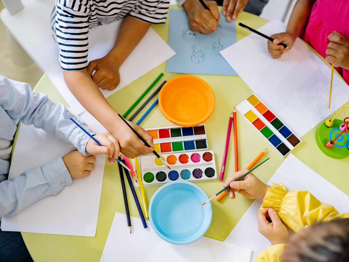 Kinder malen gemeinsam an einem Tisch mit Wasserfarben
