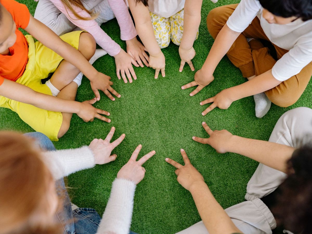 Kinderhände bilden einen Kreis auf einer Wiese